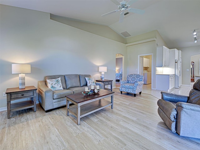 living room featuring arched walkways, washer / dryer, light wood-style flooring, ceiling fan, and baseboards