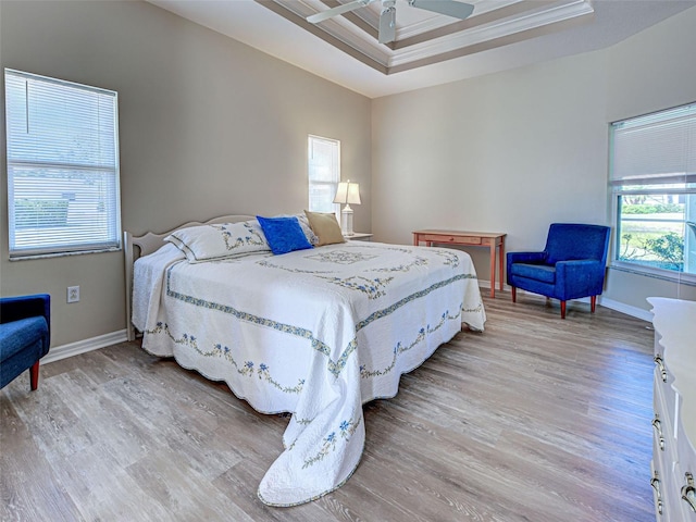 bedroom with light wood-style floors, ornamental molding, baseboards, and a ceiling fan