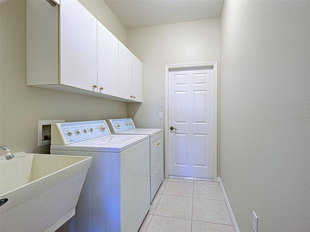washroom with cabinet space, washing machine and dryer, baseboards, light tile patterned flooring, and a textured ceiling
