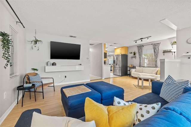 1629 Siesta Dr, Sarasota, FL 34239 - living room with baseboards, track lighting, light wood-style flooring, a textured ceiling, and visible vents