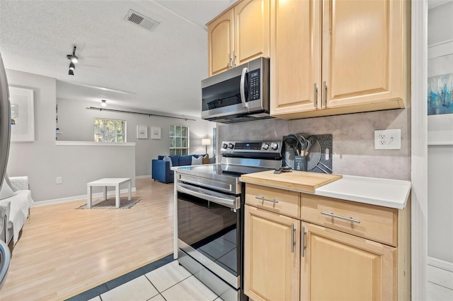 1629 Siesta Dr, Sarasota, FL 34239 - kitchen with light brown cabinets, open floor plan, light tile patterned floors, visible vents, and stainless steel appliances