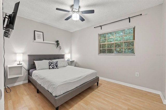 1629 Siesta Dr, Sarasota, FL 34239 - bedroom with light wood-style flooring, ceiling fan, baseboards, and a textured ceiling