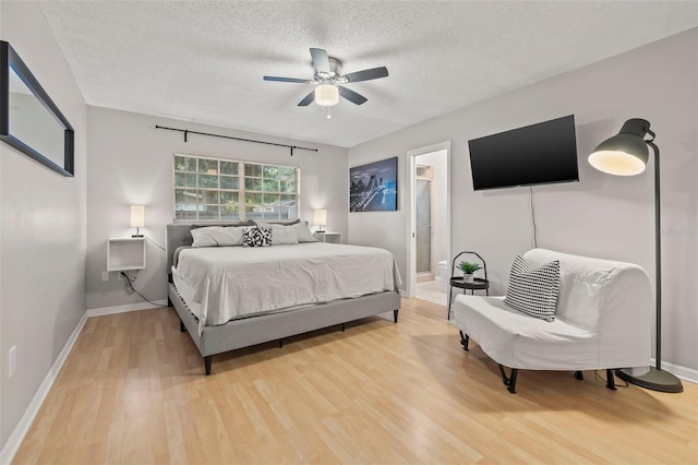 1629 Siesta Dr, Sarasota, FL 34239 - bedroom featuring baseboards, a textured ceiling, connected bathroom, light wood-style floors, and ceiling fan