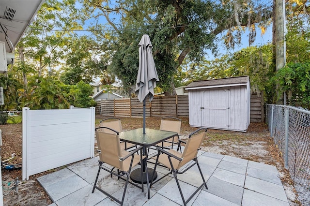 1629 Siesta Dr, Sarasota, FL 34239 - view of patio / terrace featuring a storage shed, outdoor dining space, a fenced backyard, and an outbuilding