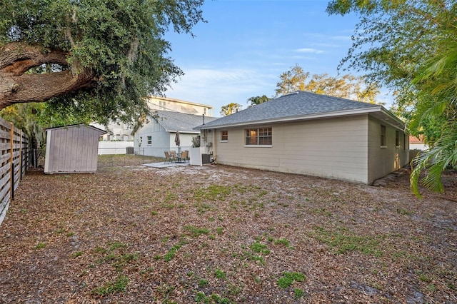 1629 Siesta Dr, Sarasota, FL 34239 - back of property with a fenced backyard, a patio, a storage unit, an outbuilding, and roof with shingles