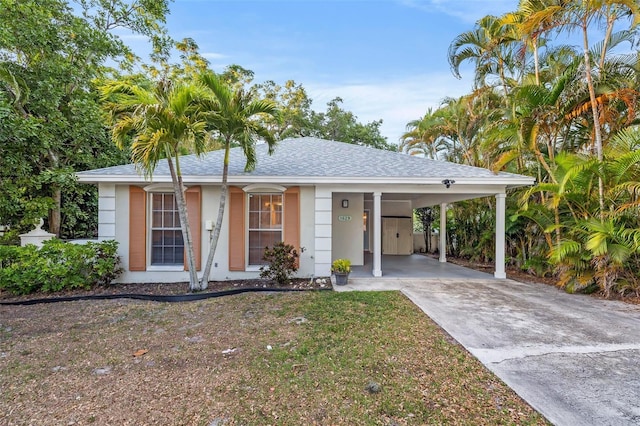 1629 Siesta Dr, Sarasota, FL 34239 - ranch-style home with stucco siding, a carport, a front lawn, a shingled roof, and concrete driveway