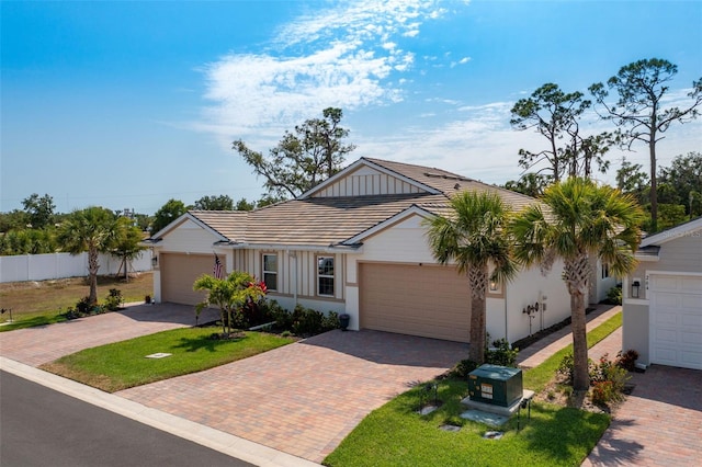 ranch-style house featuring decorative driveway, stucco siding, a garage, board and batten siding, and a tiled roof