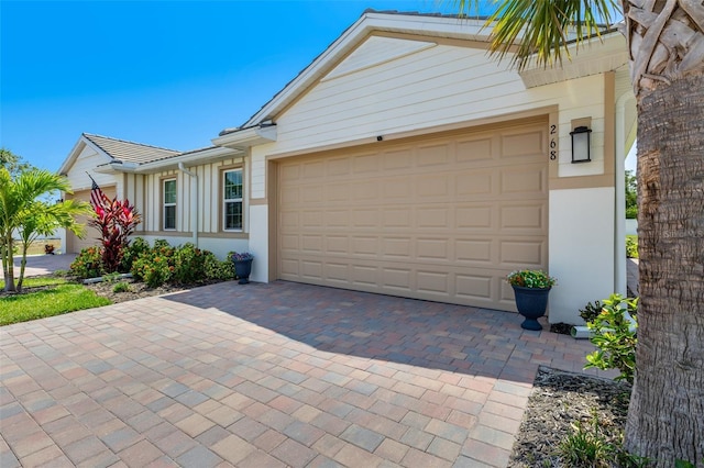 single story home featuring decorative driveway, a garage, and stucco siding