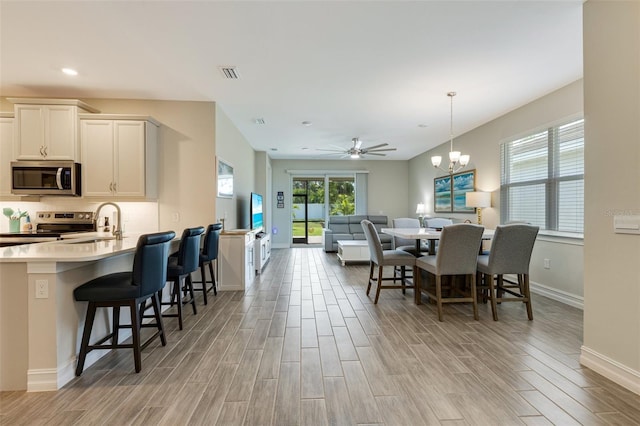 dining space with light wood finished floors, baseboards, a chandelier, recessed lighting, and a ceiling fan