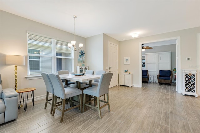 dining area featuring light wood-style flooring, a chandelier, and baseboards