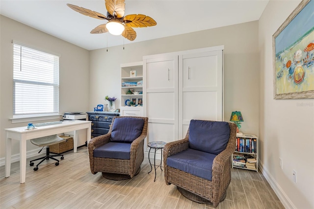 living area featuring an office area, light wood-type flooring, ceiling fan, and baseboards