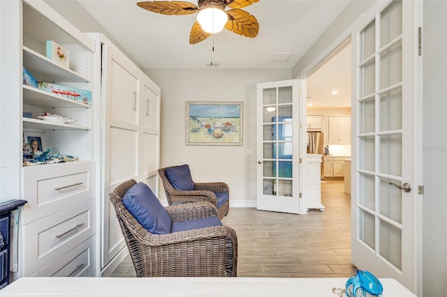 sitting room featuring french doors, light wood-style flooring, ceiling fan, and baseboards