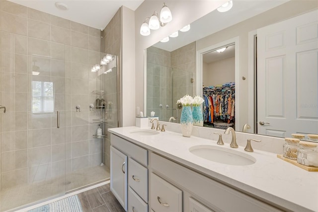 full bathroom featuring a shower stall, double vanity, and a walk in closet
