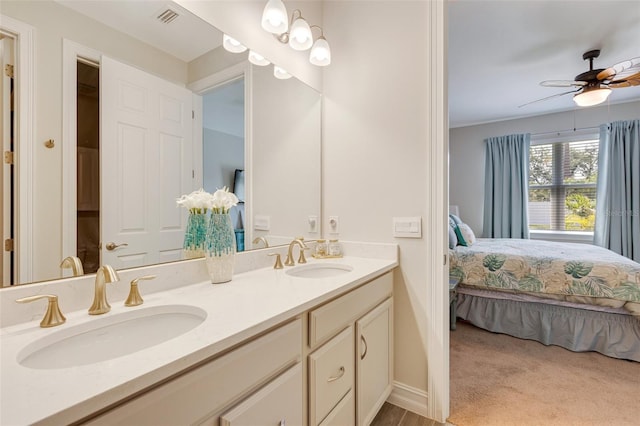 full bathroom featuring ensuite bath, double vanity, a ceiling fan, and baseboards