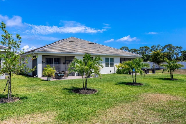 rear view of property with a yard, a patio, stucco siding, and a tile roof