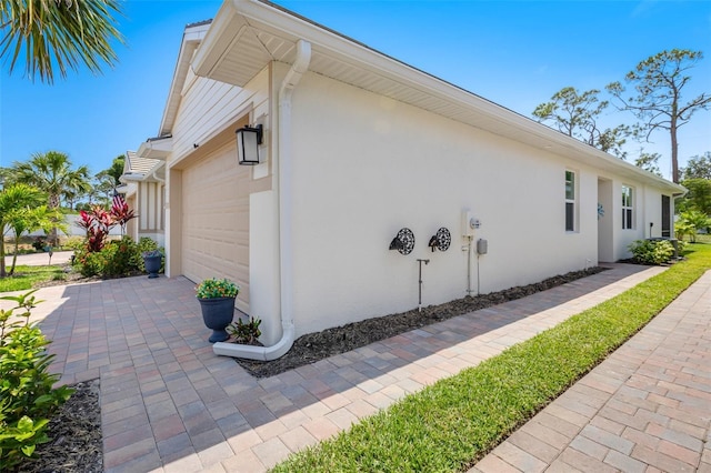 view of side of home featuring an attached garage and stucco siding