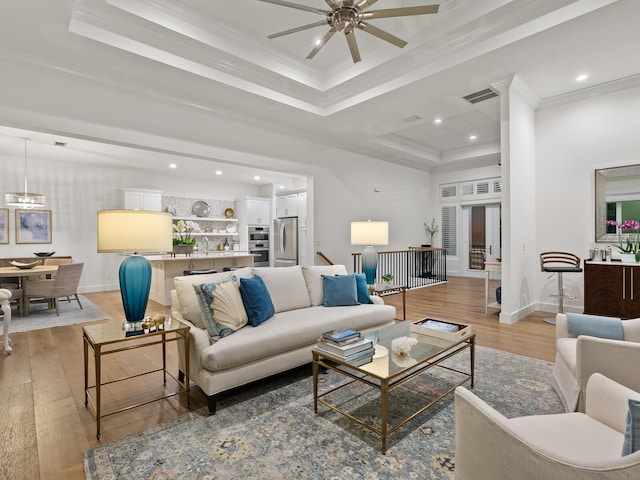 9810 Eagle Preserve Dr, Englewood, FL 34224 - living room with crown molding, a ceiling fan, light wood-type flooring, a tray ceiling, and visible vents