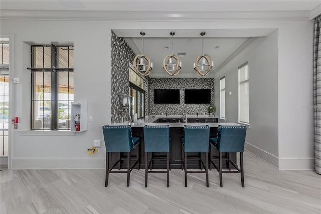 kitchen with a chandelier, crown molding, baseboards, and a breakfast bar