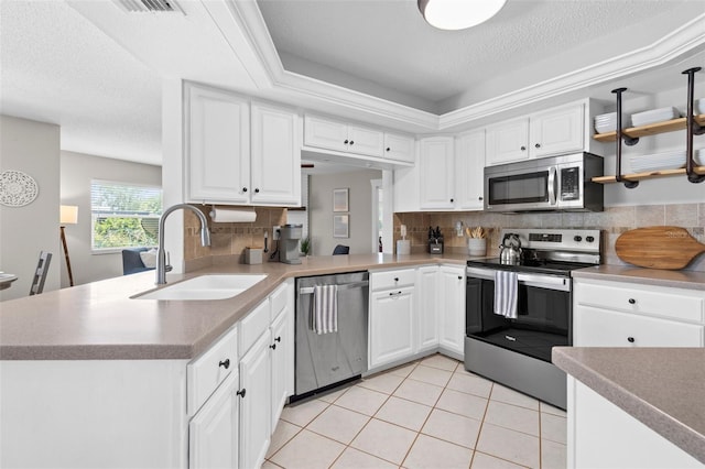 205 Cavallini Dr, Nokomis, FL 34275 - kitchen with white cabinets, stainless steel appliances, light tile patterned floors, a sink, and decorative backsplash
