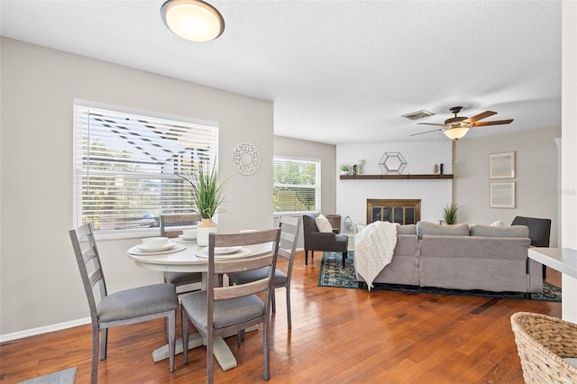 205 Cavallini Dr, Nokomis, FL 34275 - dining area featuring a ceiling fan, a textured ceiling, a fireplace, dark wood-style flooring, and visible vents