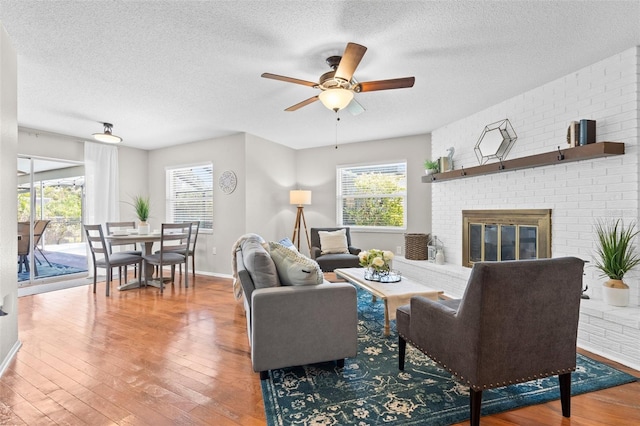 205 Cavallini Dr, Nokomis, FL 34275 - living room featuring wood-type flooring, a textured ceiling, a ceiling fan, and a fireplace