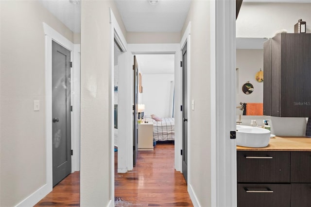 205 Cavallini Dr, Nokomis, FL 34275 - hallway featuring baseboards, wood finished floors, and a sink