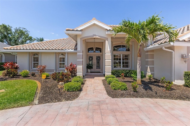 511 Governors Green Dr, Venice, FL 34293 - view of exterior entry featuring stucco siding, a tiled roof, and french doors