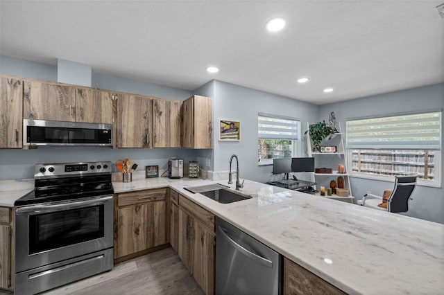 3355 Roslyn Rd, Venice, FL 34293 - kitchen featuring brown cabinetry, stainless steel appliances, light wood finished floors, and a sink