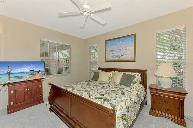 bedroom with light colored carpet, baseboards, and multiple windows
