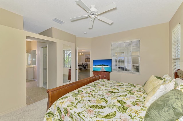 carpeted bedroom featuring tile patterned floors, visible vents, a ceiling fan, and ensuite bathroom