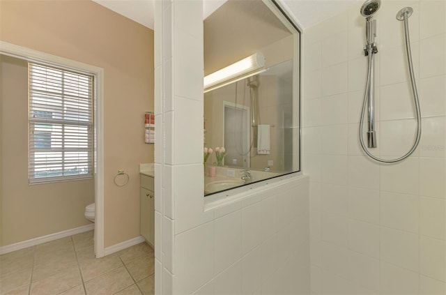 full bath with tiled shower, tile patterned floors, toilet, vanity, and baseboards