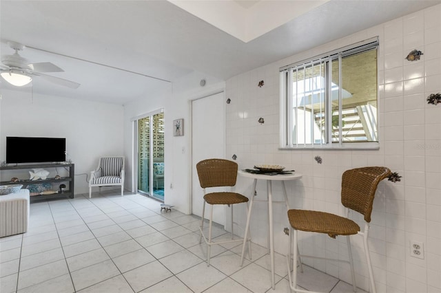 360 Base Ave E Unit 413, Venice, FL 34285 - living area with light tile patterned flooring, tile walls, and a ceiling fan