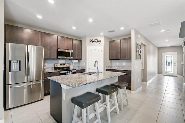 4523 Birdsong Dr, Palmetto, FL 34221 - kitchen featuring a kitchen breakfast bar, dark brown cabinets, light tile patterned floors, a sink, and appliances with stainless steel finishes