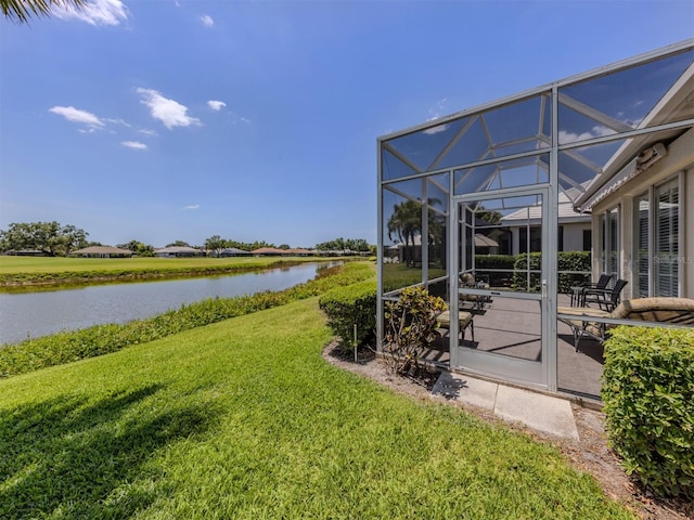 view of yard with glass enclosure, a water view, and a patio area