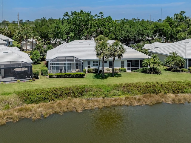 back of house featuring a lanai, a water view, and a yard