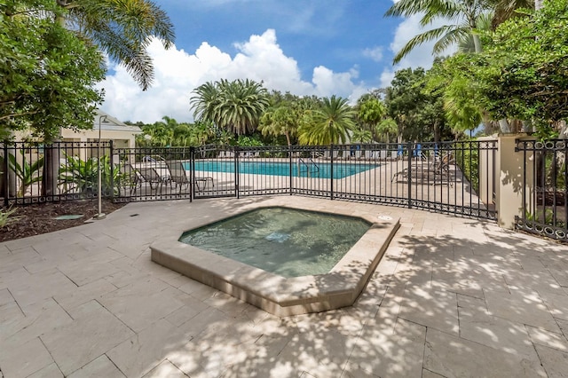 community pool featuring fence, a patio, and a community hot tub
