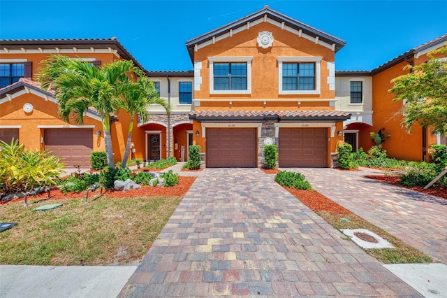 view of front of house featuring a tiled roof, a garage, stucco siding, and driveway
