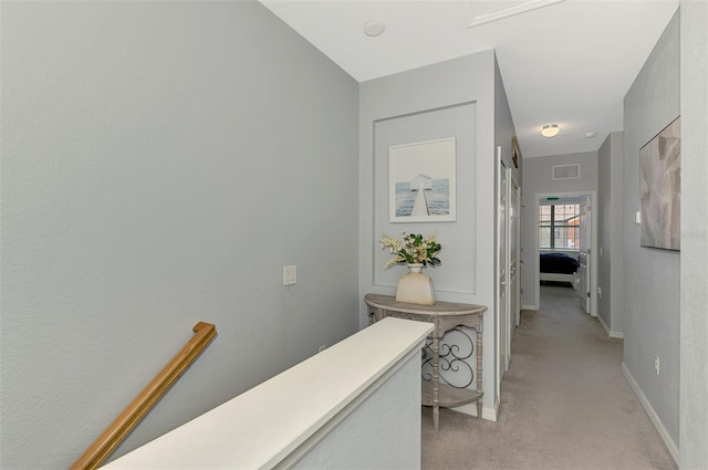 corridor featuring visible vents, baseboards, and light carpet