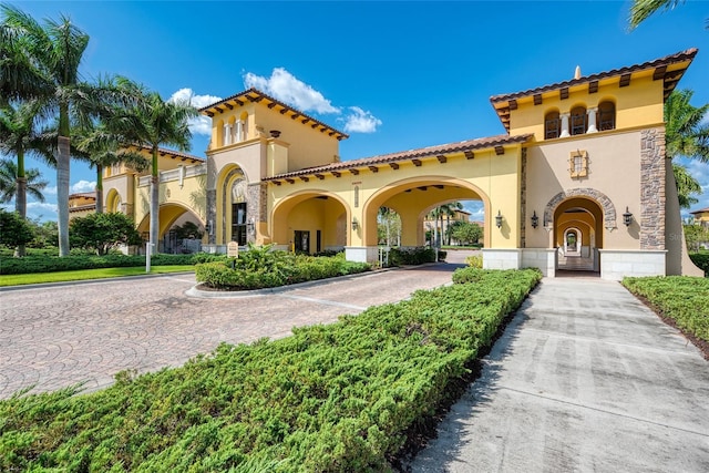 mediterranean / spanish home featuring a tiled roof, stone siding, and stucco siding