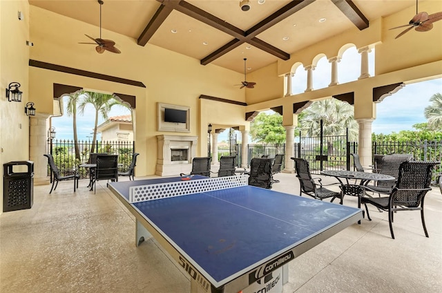 view of patio with an outdoor fireplace, fence, and a ceiling fan
