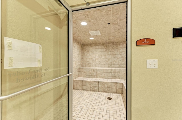 full bathroom with recessed lighting, a textured wall, and a stall shower