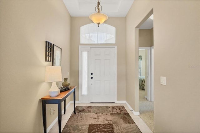tiled foyer with baseboards and a towering ceiling
