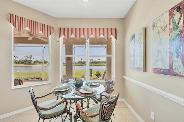tiled dining area with plenty of natural light, a water view, and baseboards