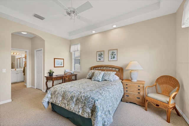 bedroom with carpet, a tray ceiling, visible vents, arched walkways, and baseboards