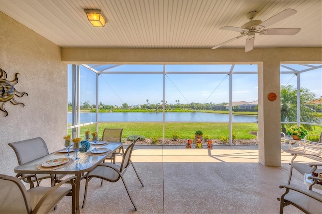 view of patio with a ceiling fan, glass enclosure, and a water view