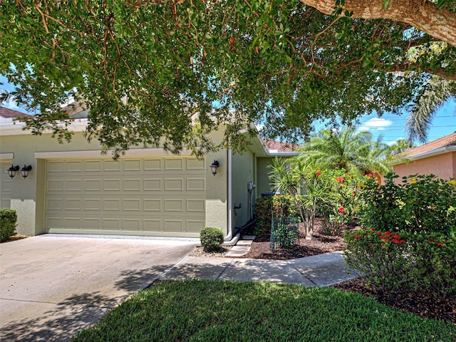view of property hidden behind natural elements with an attached garage, driveway, and stucco siding