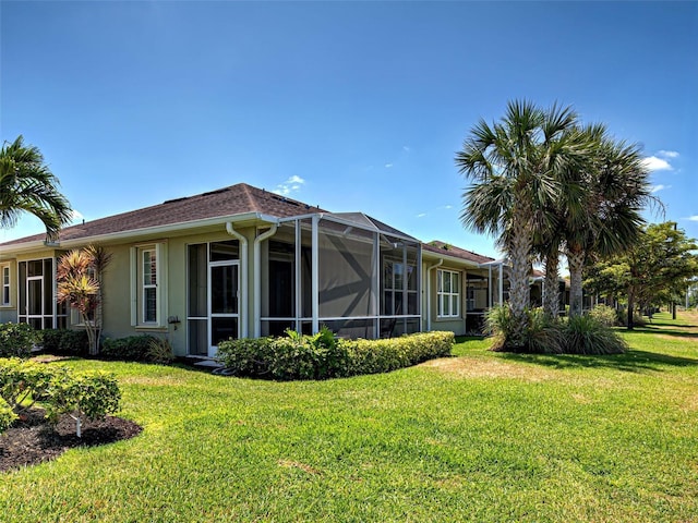 rear view of property with a lawn and stucco siding