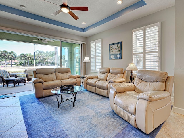 tiled living room with a healthy amount of sunlight, recessed lighting, a raised ceiling, and ceiling fan