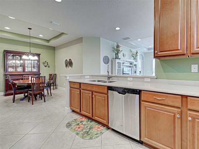 kitchen with a raised ceiling, light countertops, dishwasher, and a sink