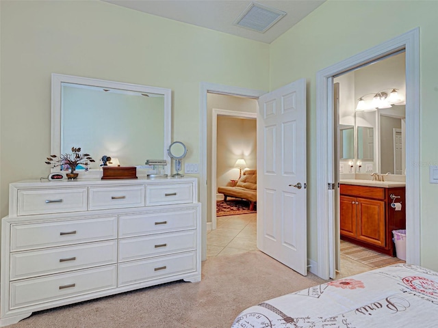 bedroom with a sink, visible vents, ensuite bathroom, and light carpet